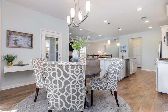 dining area with a chandelier, sink, and wood-type flooring