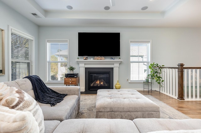 living room featuring light wood-type flooring and a tray ceiling