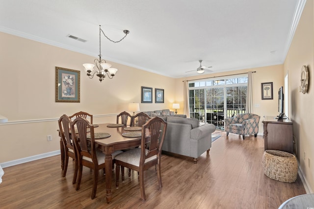 dining space with hardwood / wood-style flooring, ornamental molding, and ceiling fan with notable chandelier