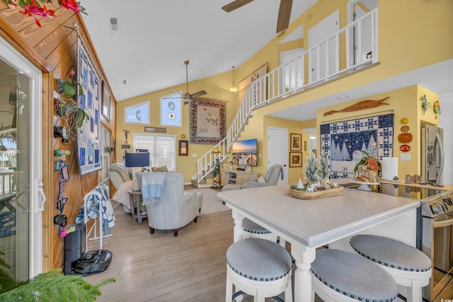 dining room with ceiling fan, high vaulted ceiling, and light hardwood / wood-style flooring