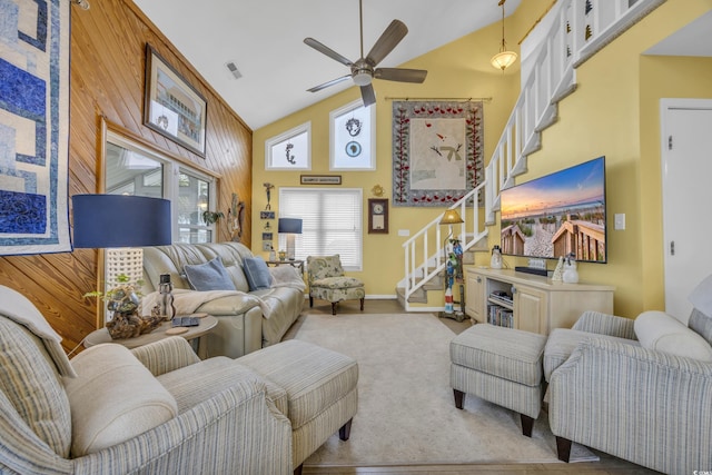 living room with high vaulted ceiling, ceiling fan, and wood walls