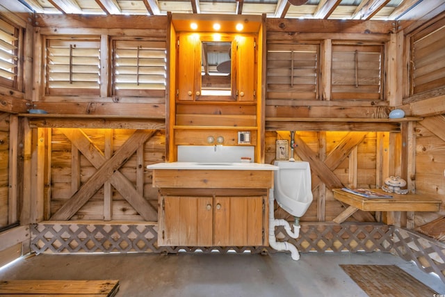 bathroom featuring wooden walls and concrete floors