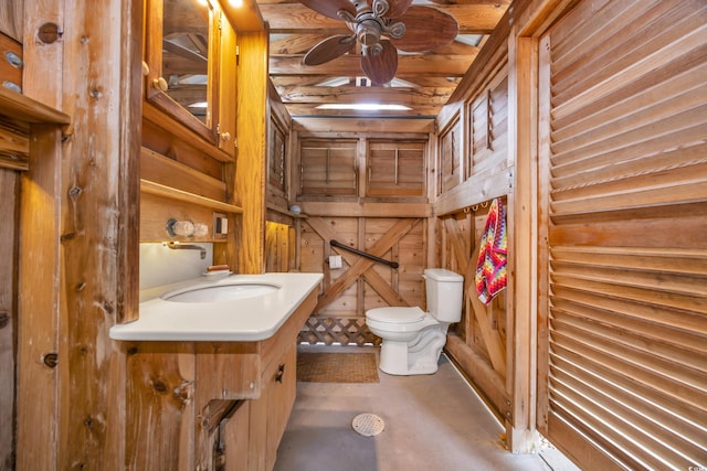 bathroom featuring vanity, wood walls, toilet, and ceiling fan