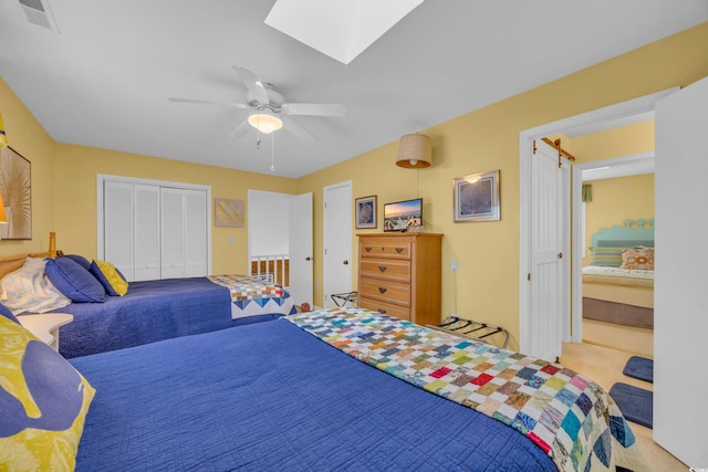 bedroom with a skylight, ceiling fan, a closet, and light carpet