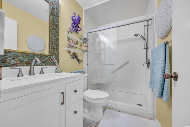 bathroom featuring vanity, a shower with shower door, and toilet