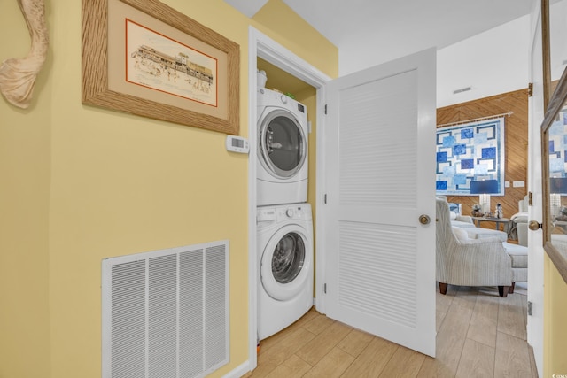 laundry area with stacked washing maching and dryer and light hardwood / wood-style flooring