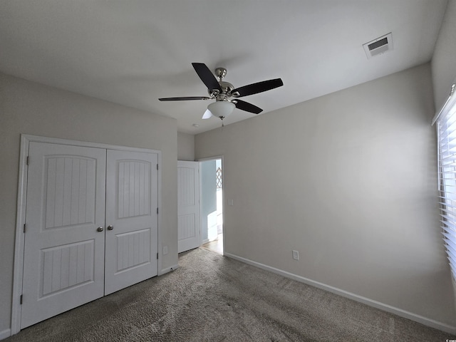 unfurnished bedroom with ceiling fan, dark carpet, and a closet