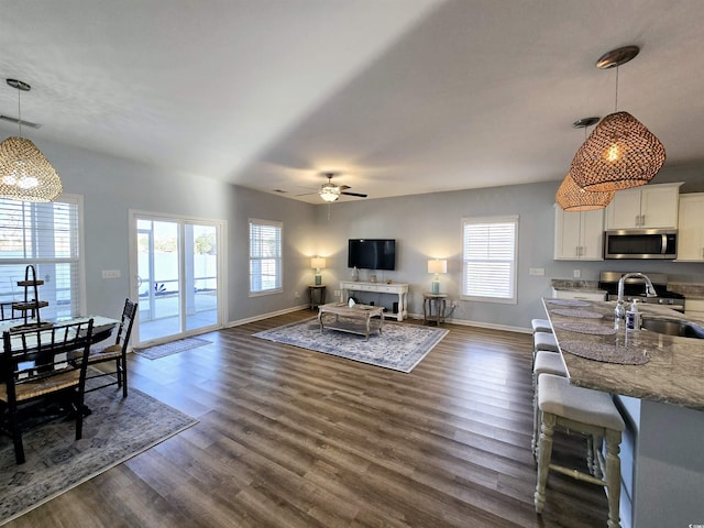 living room with dark hardwood / wood-style floors, ceiling fan, and sink