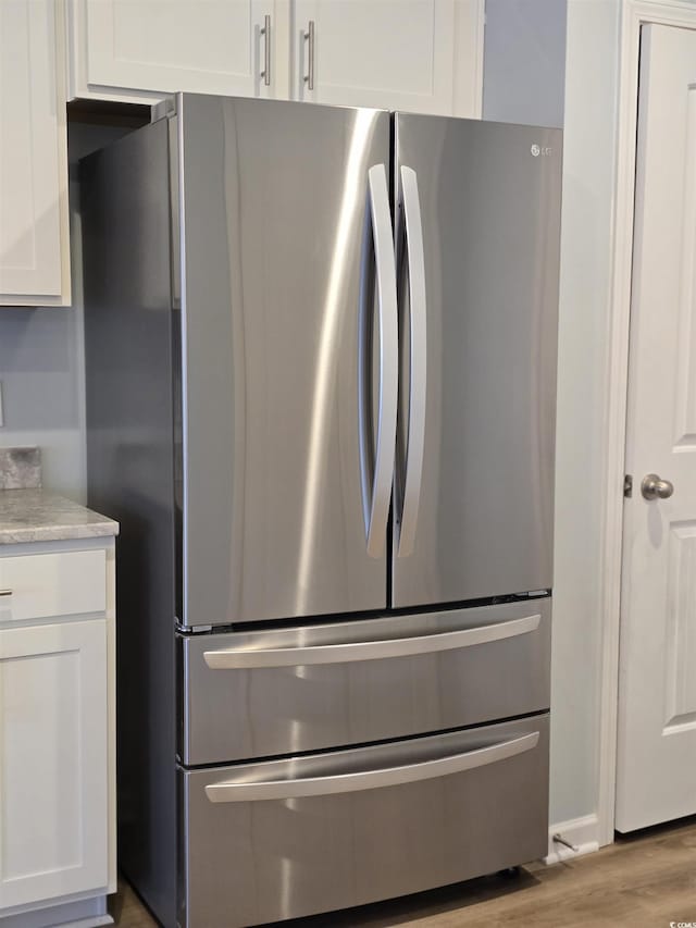 kitchen with white cabinetry, stainless steel refrigerator, and light hardwood / wood-style flooring