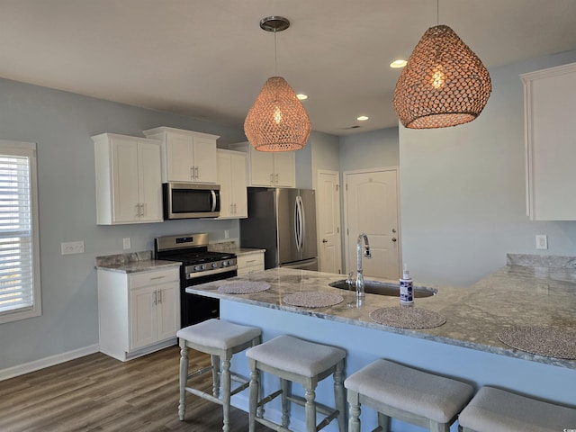 kitchen with kitchen peninsula, stainless steel appliances, sink, decorative light fixtures, and white cabinets