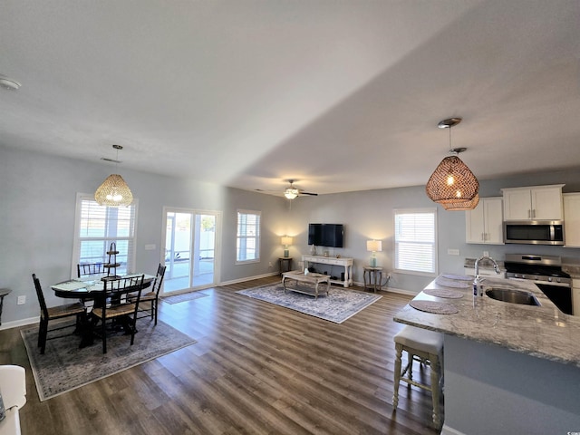 interior space featuring pendant lighting, white cabinets, sink, light stone countertops, and stainless steel appliances