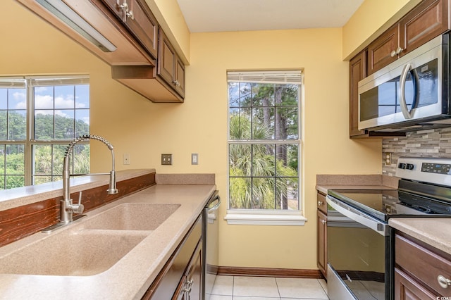 kitchen with appliances with stainless steel finishes, backsplash, sink, and light tile patterned floors