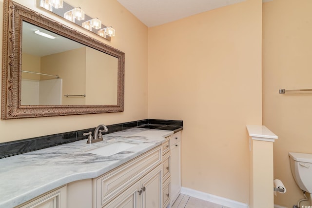 bathroom with toilet, vanity, and tile patterned floors