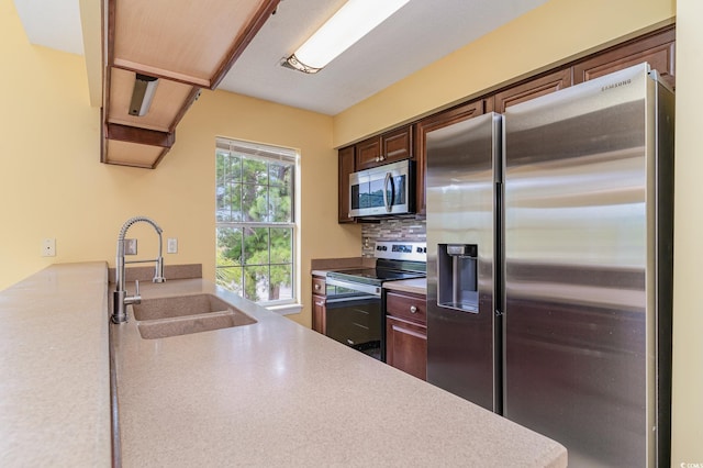 kitchen featuring appliances with stainless steel finishes, a healthy amount of sunlight, backsplash, and sink