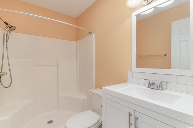 bathroom with toilet, a shower, vanity, and backsplash