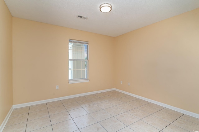 tiled empty room featuring a textured ceiling