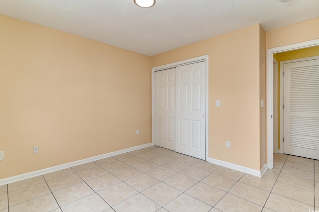 unfurnished bedroom with a textured ceiling, a closet, and light tile patterned flooring