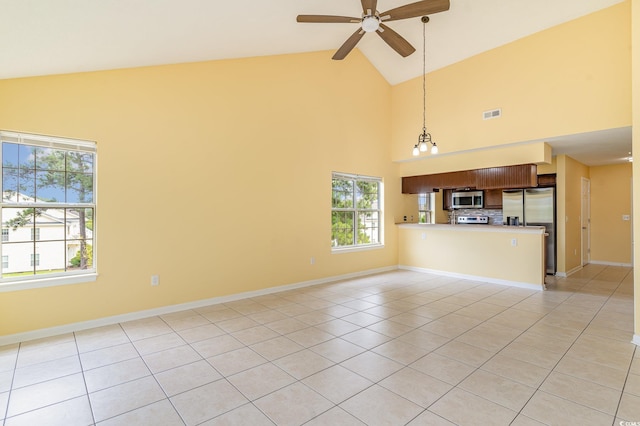 unfurnished living room featuring ceiling fan with notable chandelier, high vaulted ceiling, and light tile patterned floors