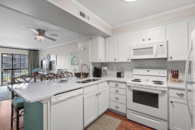 kitchen with white cabinetry, sink, kitchen peninsula, white appliances, and a breakfast bar