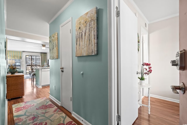 hallway with light hardwood / wood-style flooring and crown molding