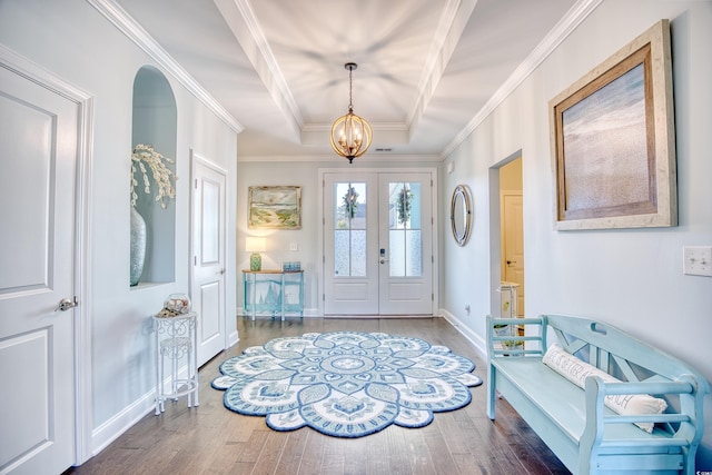 foyer with french doors, ornamental molding, a raised ceiling, dark wood-type flooring, and a chandelier