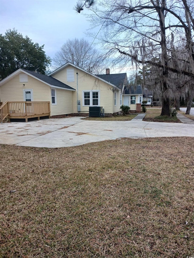 view of side of home featuring central AC unit, a yard, and a wooden deck