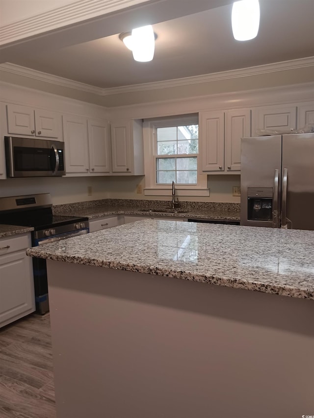 kitchen with white cabinets, ornamental molding, light stone counters, and appliances with stainless steel finishes