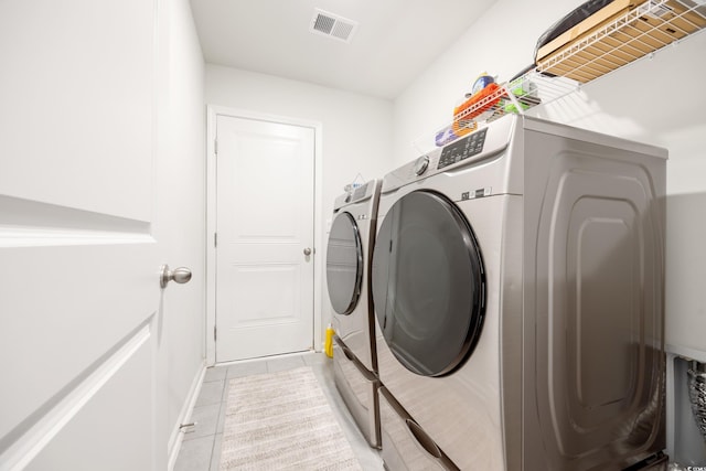 clothes washing area with washing machine and dryer and light tile patterned floors