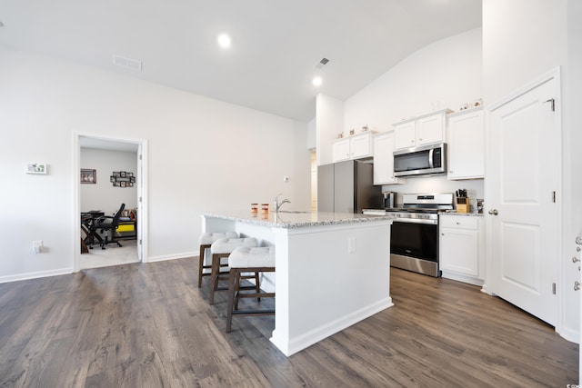 kitchen with white cabinets, lofted ceiling, an island with sink, and appliances with stainless steel finishes