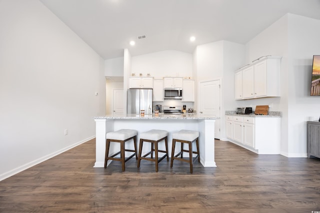 kitchen featuring a kitchen breakfast bar, white cabinetry, stainless steel appliances, and an island with sink