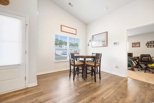 dining room featuring wood-type flooring and vaulted ceiling