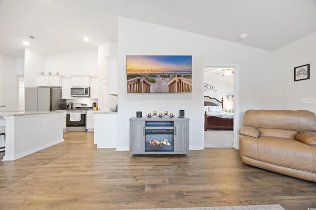 living room with hardwood / wood-style flooring, ceiling fan, and lofted ceiling