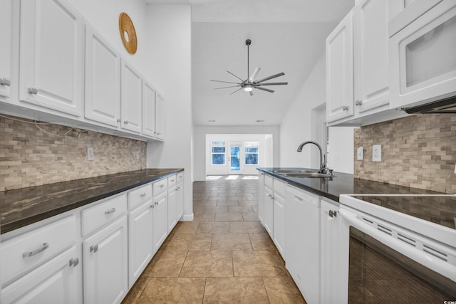 kitchen featuring lofted ceiling, white appliances, sink, decorative backsplash, and white cabinetry