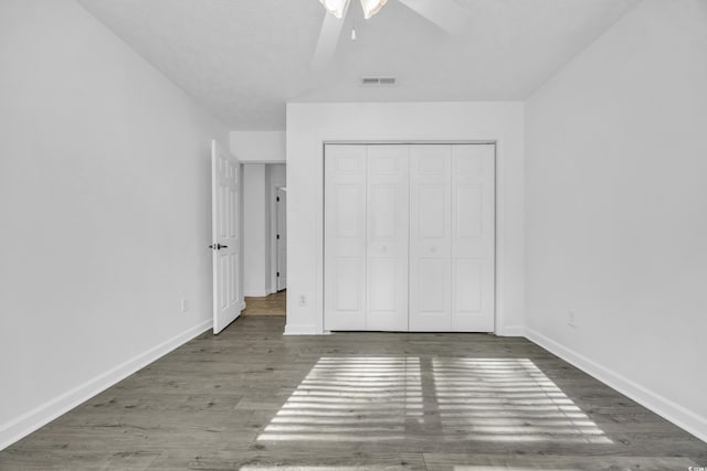 unfurnished bedroom with dark hardwood / wood-style flooring, a closet, and ceiling fan