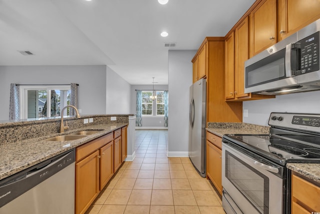 kitchen featuring light stone counters, stainless steel appliances, sink, light tile patterned floors, and a chandelier