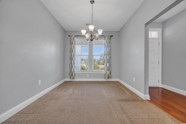 spare room featuring a chandelier, carpet floors, and a healthy amount of sunlight