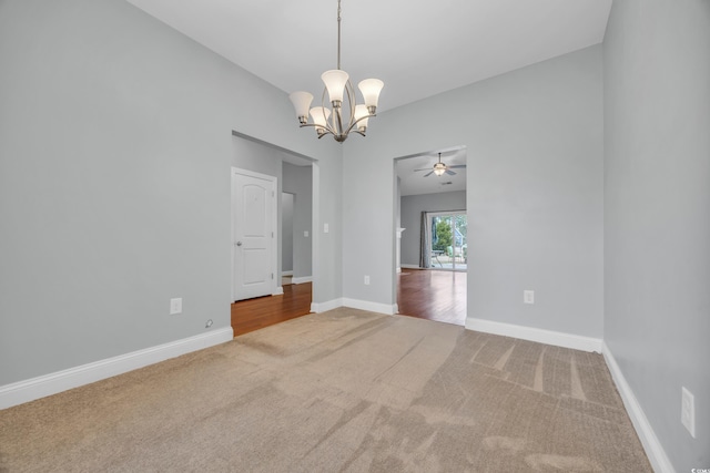 carpeted empty room featuring ceiling fan with notable chandelier