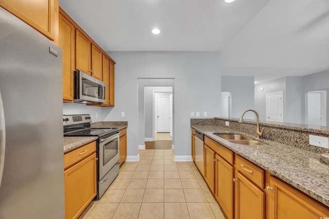 kitchen with light stone countertops, appliances with stainless steel finishes, light tile patterned floors, and sink