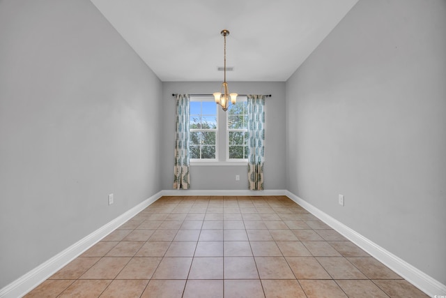 tiled spare room featuring a chandelier