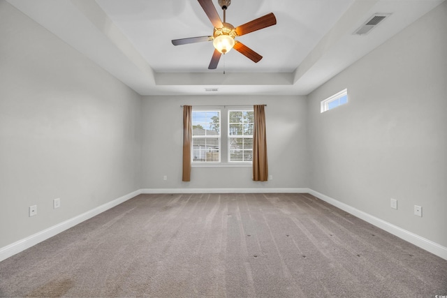 carpeted empty room featuring a raised ceiling and ceiling fan