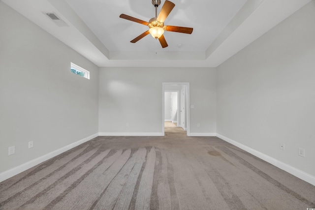 spare room featuring light carpet, a raised ceiling, and ceiling fan