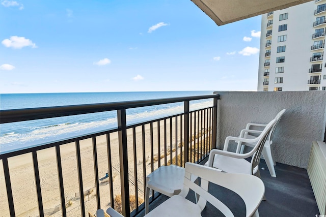 balcony with radiator, a view of the beach, and a water view