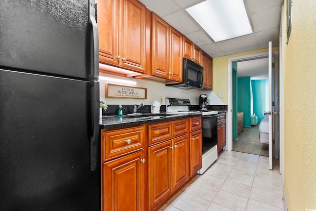 kitchen with sink, a drop ceiling, black appliances, and light tile patterned flooring