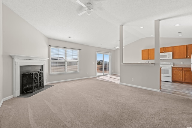 unfurnished living room with vaulted ceiling, light carpet, ceiling fan, and a textured ceiling