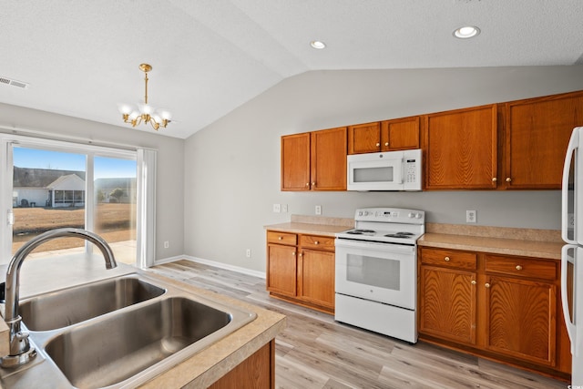 kitchen featuring pendant lighting, white appliances, lofted ceiling, sink, and a notable chandelier