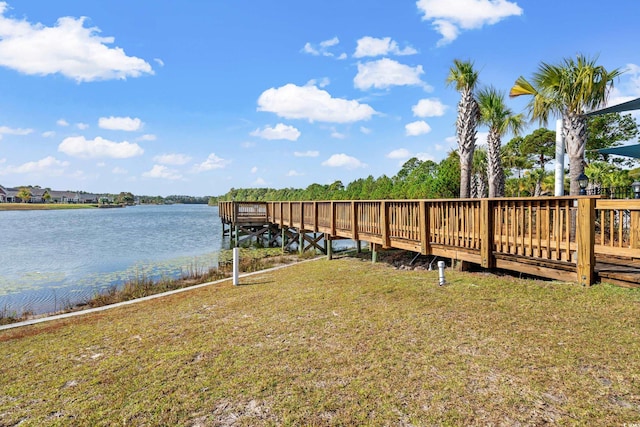 view of dock with a lawn and a water view