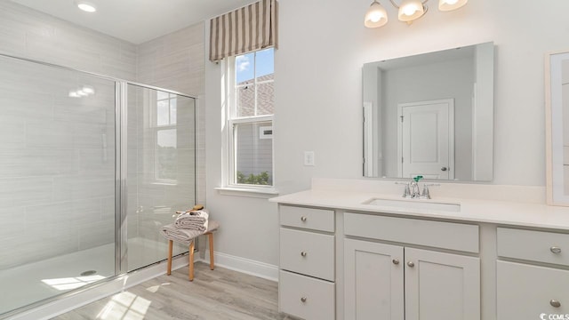 bathroom featuring a shower stall, vanity, baseboards, and wood finished floors