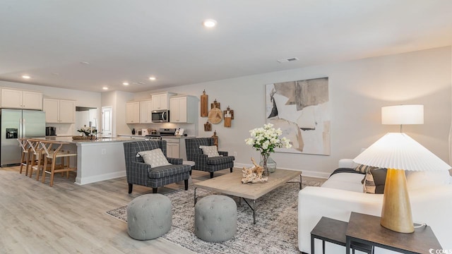 living room with recessed lighting, light wood finished floors, and baseboards