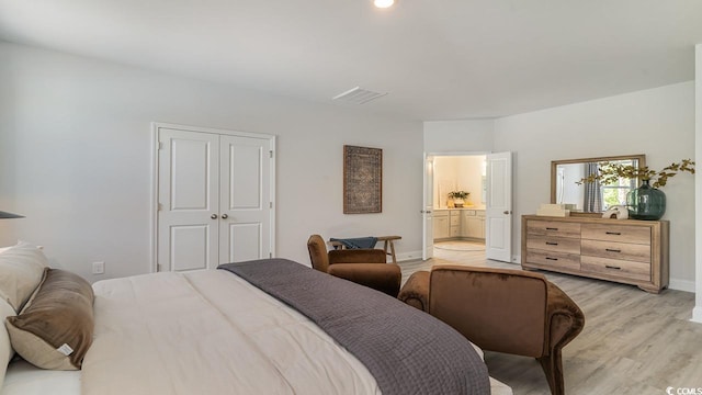 bedroom with light wood-style floors, baseboards, a closet, and ensuite bath