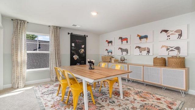 carpeted dining space with baseboards and a barn door